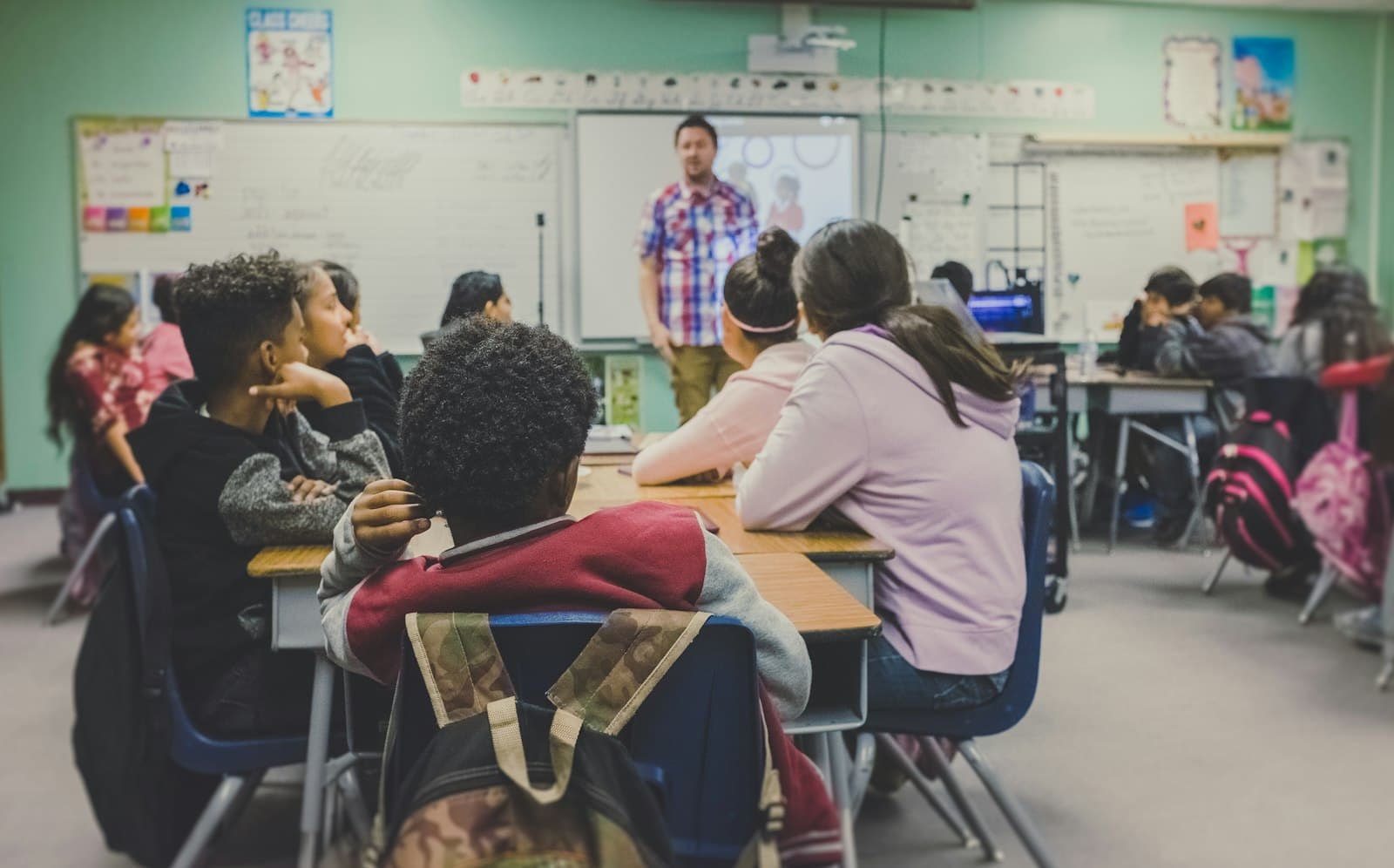 A teacher working through a problem with students at a whiteboard
